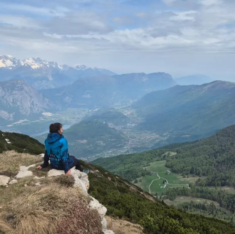 Stela Nemčev standing on a mountain ridge, looking out over a forested valley